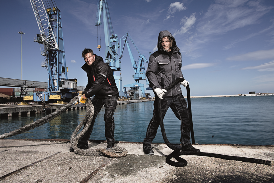 Two workers in Sir Safety Fusion workwear hauling a mooring rope on a harbour quay